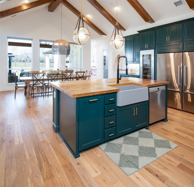 kitchen featuring a sink, appliances with stainless steel finishes, wood counters, and light wood-style flooring