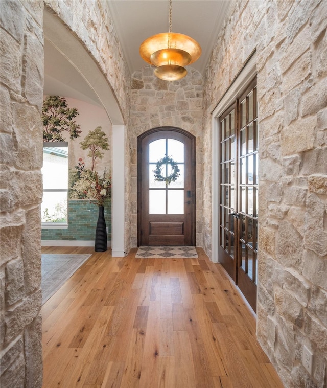 entrance foyer featuring plenty of natural light, arched walkways, crown molding, and hardwood / wood-style floors