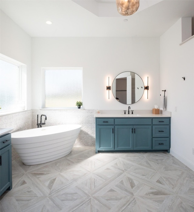 full bath featuring a soaking tub, vanity, and recessed lighting