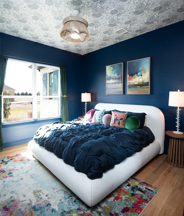 bedroom featuring a textured ceiling, visible vents, and wood finished floors