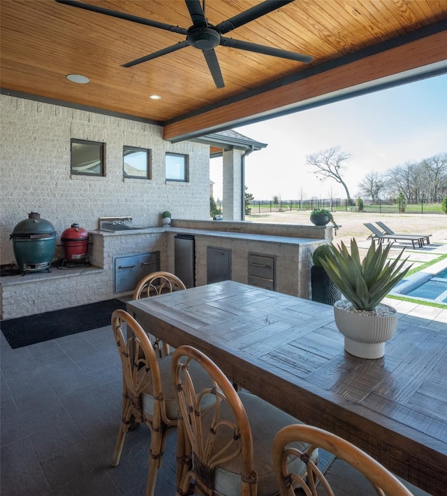 view of patio / terrace featuring a ceiling fan, grilling area, fence, exterior kitchen, and outdoor wet bar