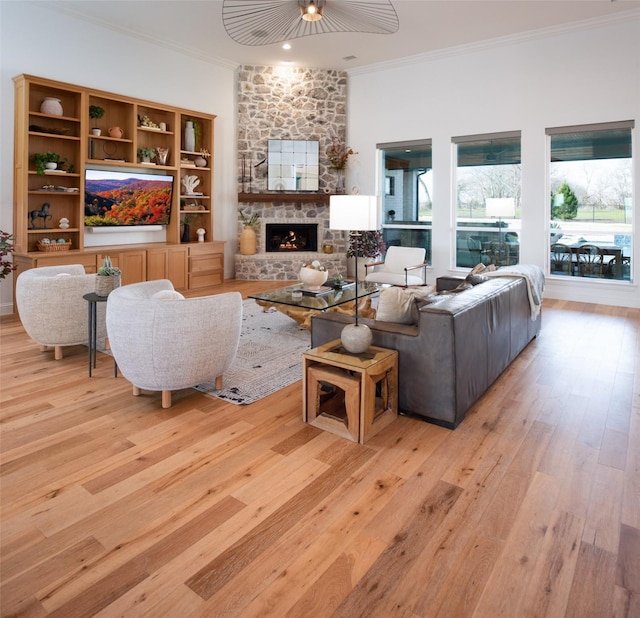 living room with light wood finished floors, a fireplace, and crown molding