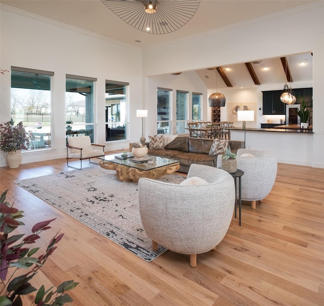 living area with baseboards, a towering ceiling, crown molding, light wood-style floors, and beam ceiling