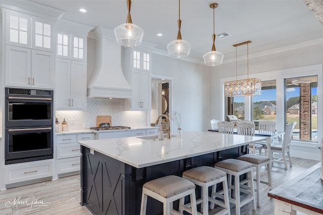 kitchen featuring double oven, a sink, visible vents, backsplash, and custom range hood