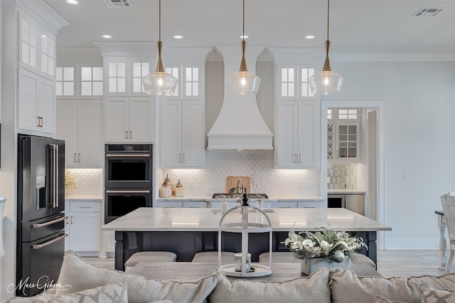 kitchen with double oven, a breakfast bar, high end refrigerator, visible vents, and ornamental molding