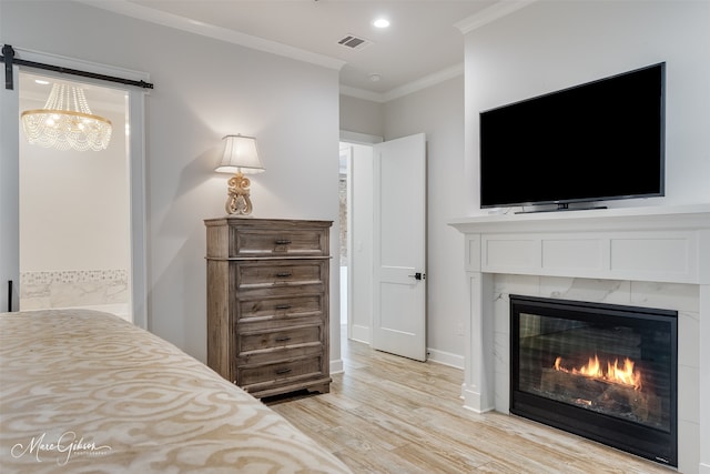 bedroom featuring visible vents, baseboards, ornamental molding, light wood-style floors, and a fireplace