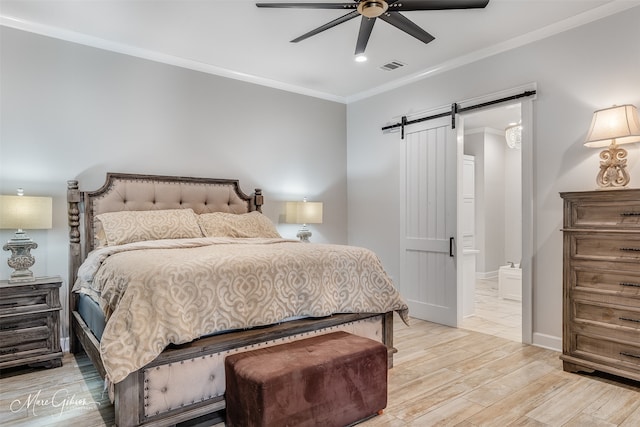 bedroom with crown molding, visible vents, light wood-style flooring, a barn door, and baseboards