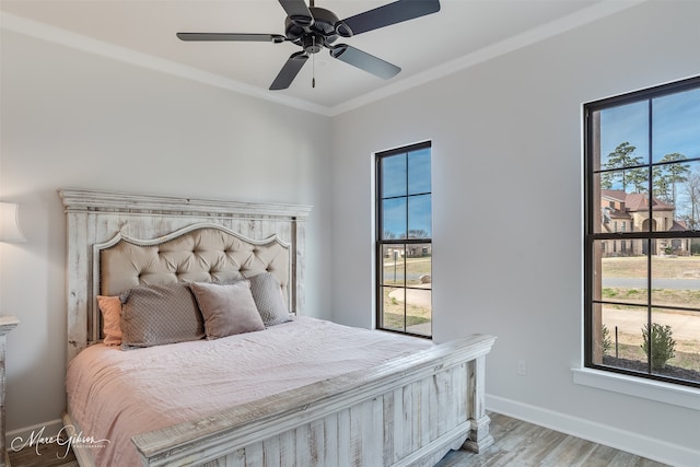 bedroom featuring multiple windows, baseboards, wood finished floors, and ornamental molding