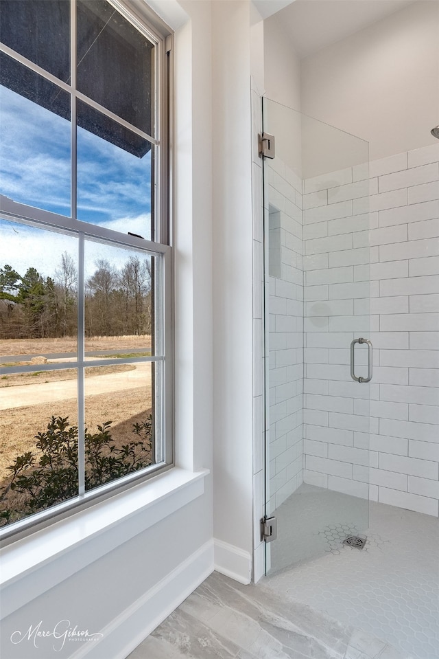 bathroom featuring a healthy amount of sunlight, a shower stall, and baseboards