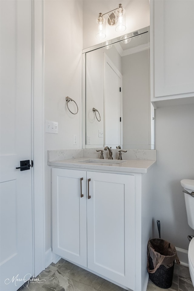 half bathroom with toilet, ornamental molding, and vanity