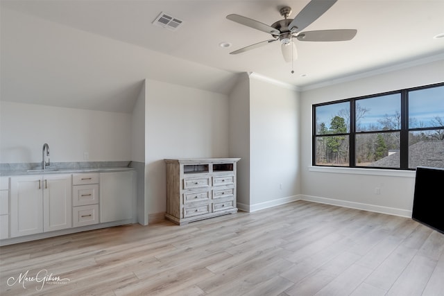 interior space with light wood-type flooring, baseboards, visible vents, and a sink