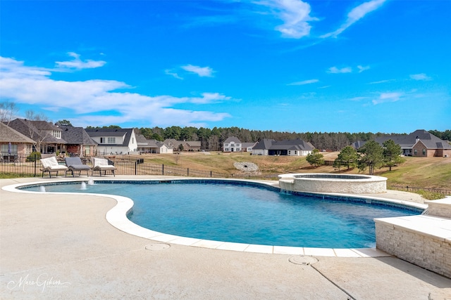 view of swimming pool featuring a patio area, a pool with connected hot tub, a residential view, and fence