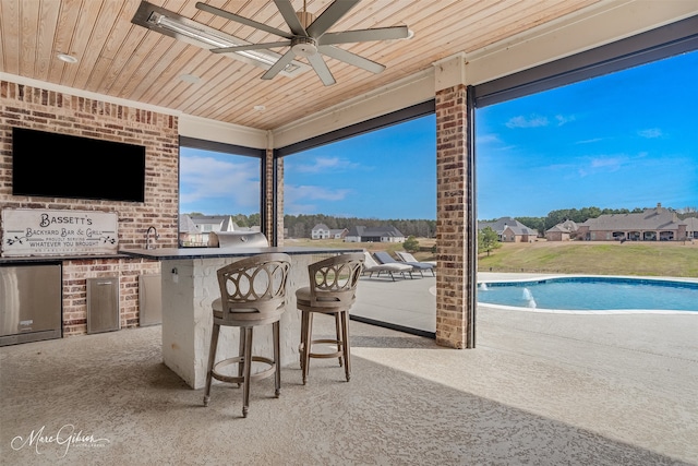 view of patio / terrace featuring ceiling fan, exterior kitchen, a residential view, outdoor wet bar, and an outdoor pool