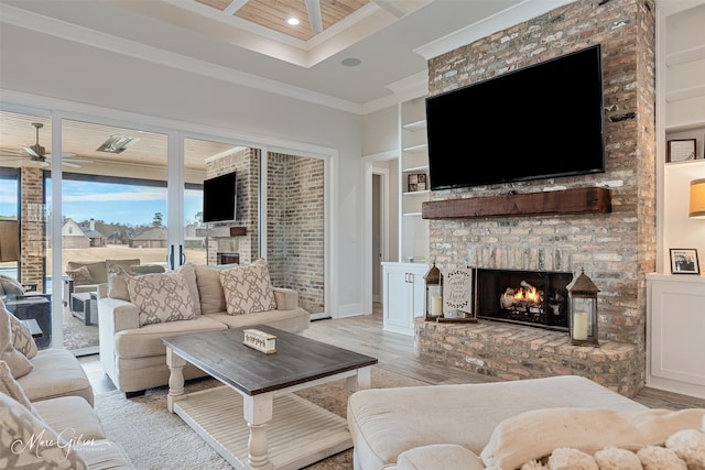 living area with ceiling fan, ornamental molding, light wood-type flooring, built in shelves, and a fireplace