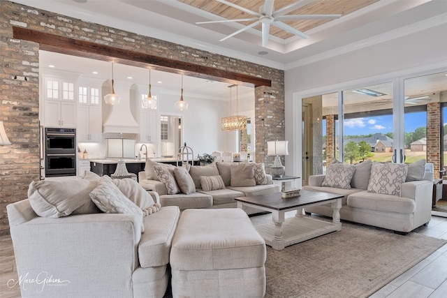 living room with recessed lighting, a raised ceiling, light wood-style flooring, ornamental molding, and ceiling fan