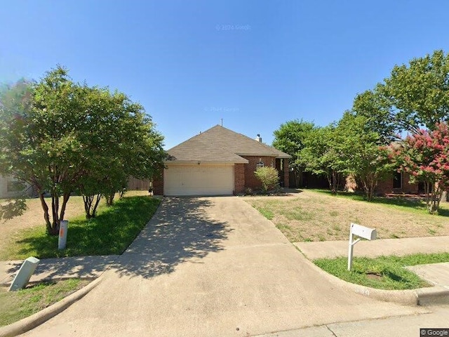 view of front of property featuring driveway, brick siding, a front lawn, and an attached garage