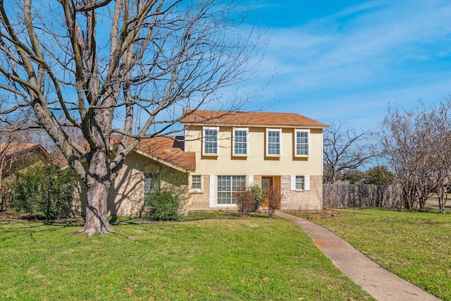 view of front facade with a front yard, fence, brick siding, and stucco siding