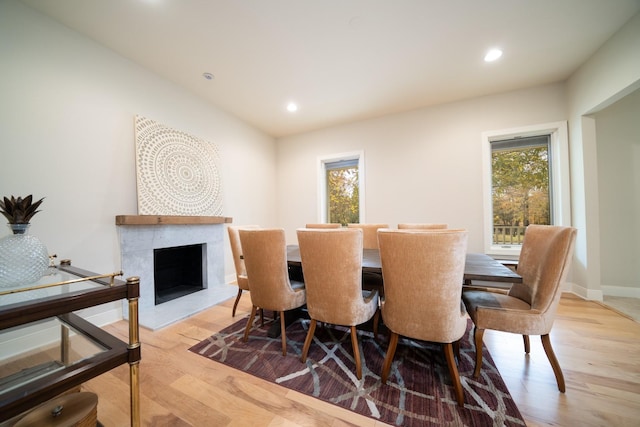 dining space with a healthy amount of sunlight, a fireplace with raised hearth, and wood finished floors