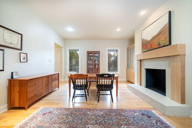 dining room featuring light wood-type flooring, a fireplace, baseboards, and recessed lighting