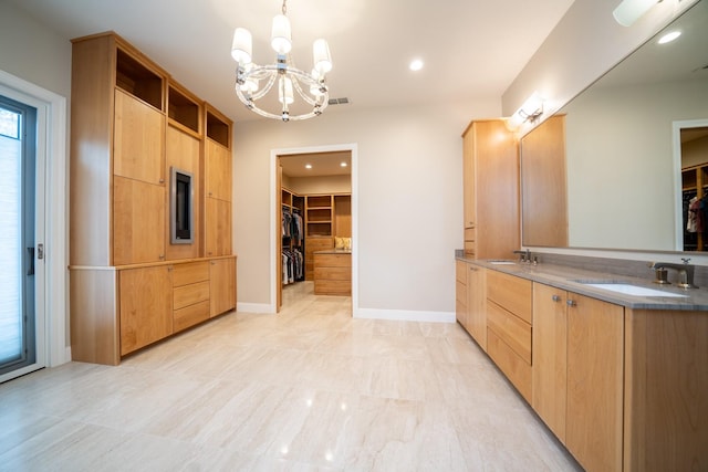 bathroom with a walk in closet, a sink, baseboards, and double vanity