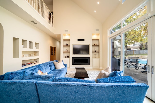 living area with built in features, visible vents, a fireplace, and high vaulted ceiling