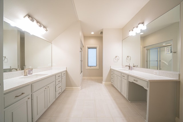 full bath with two vanities, a sink, a shower with shower door, and baseboards