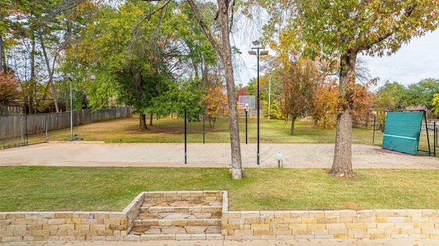 view of yard with community basketball court and fence