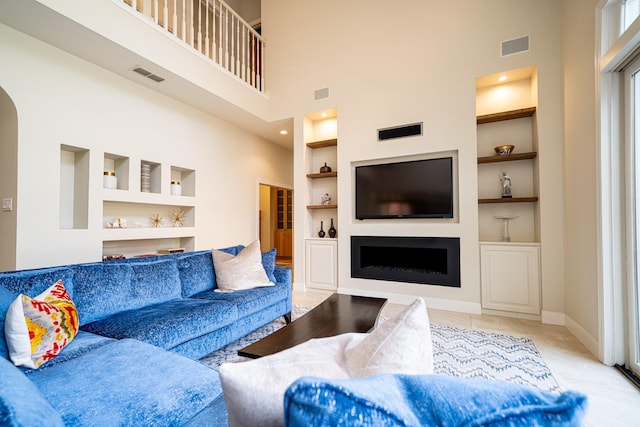 living area featuring arched walkways, baseboards, visible vents, and built in features