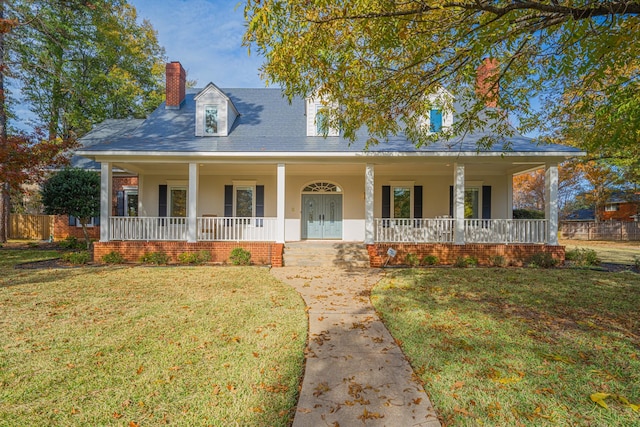 view of front of property featuring covered porch, a front lawn, a chimney, and stucco siding