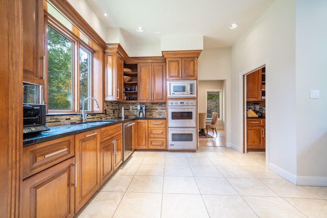 kitchen with open shelves, backsplash, appliances with stainless steel finishes, brown cabinetry, and a sink