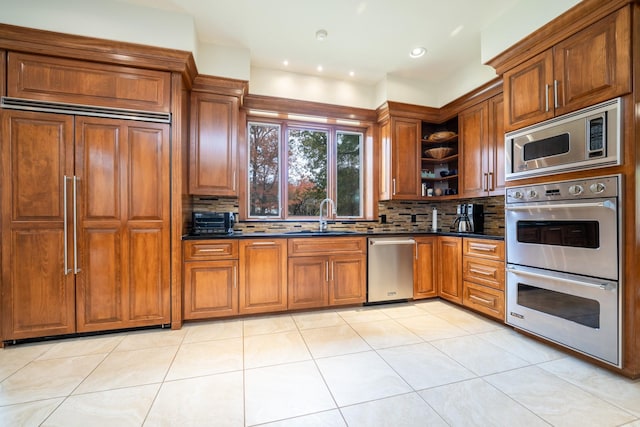 kitchen featuring built in appliances, open shelves, dark countertops, and a sink