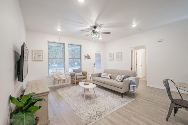 living area with light wood finished floors, baseboards, and a ceiling fan