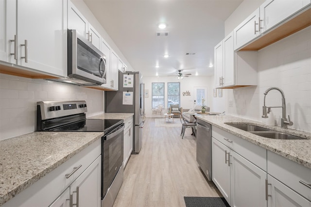 kitchen with light wood finished floors, stainless steel appliances, visible vents, a ceiling fan, and a sink