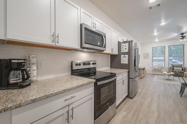 kitchen with tasteful backsplash, visible vents, white cabinets, appliances with stainless steel finishes, and light wood-style floors