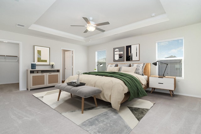 bedroom with a raised ceiling, light carpet, and multiple windows