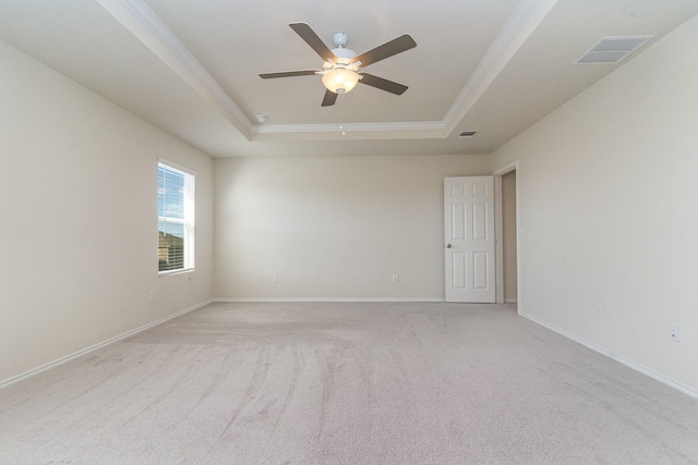 unfurnished room with ceiling fan, light carpet, visible vents, baseboards, and a tray ceiling