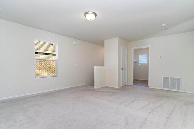 spare room with visible vents, light carpet, and baseboards