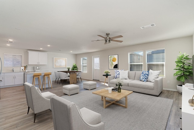 living room featuring baseboards, visible vents, ceiling fan, light wood-style floors, and recessed lighting