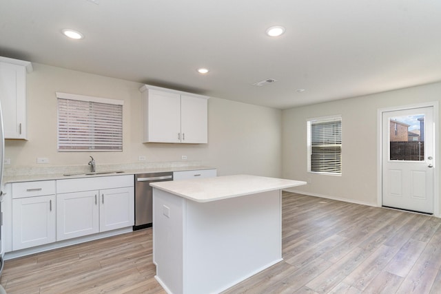 kitchen with stainless steel dishwasher, light wood-style flooring, a sink, and visible vents