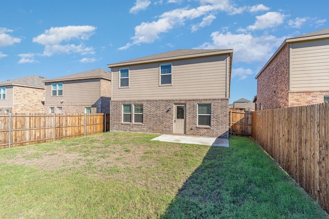 rear view of house featuring a patio area, a fenced backyard, a yard, and brick siding