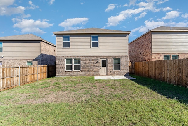 back of house with a fenced backyard, a yard, brick siding, and a patio