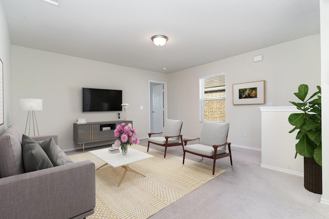 living area featuring light carpet and baseboards