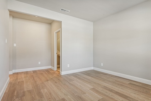 spare room with light wood-style flooring, visible vents, and baseboards