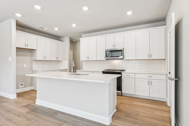 kitchen featuring a sink, visible vents, an island with sink, white cabinetry, and appliances with stainless steel finishes