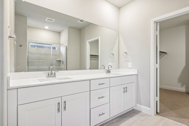 bathroom featuring a stall shower, visible vents, a sink, and a spacious closet