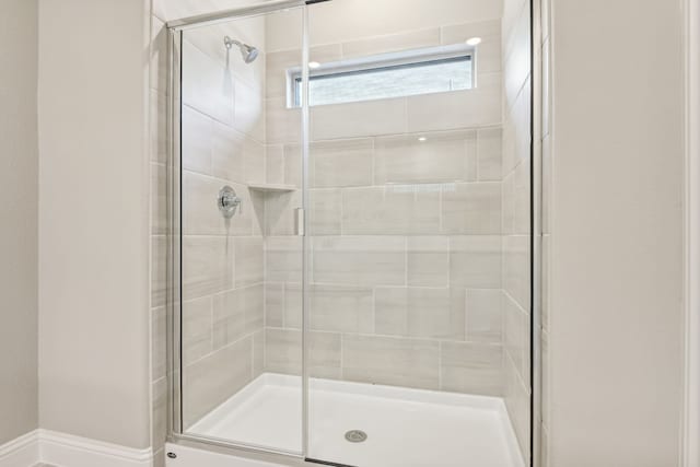 full bathroom with a shower stall and baseboards