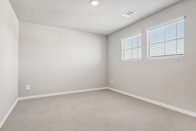 carpeted empty room with visible vents and baseboards