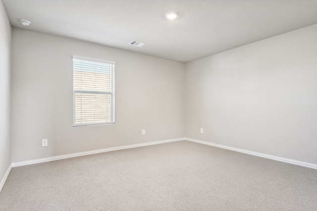 carpeted empty room featuring baseboards and visible vents