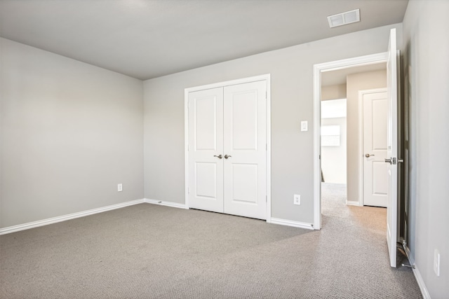 unfurnished bedroom with a closet, carpet flooring, visible vents, and baseboards