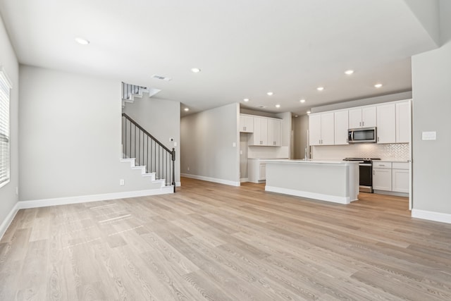 unfurnished living room featuring light wood-style flooring, stairway, visible vents, and recessed lighting